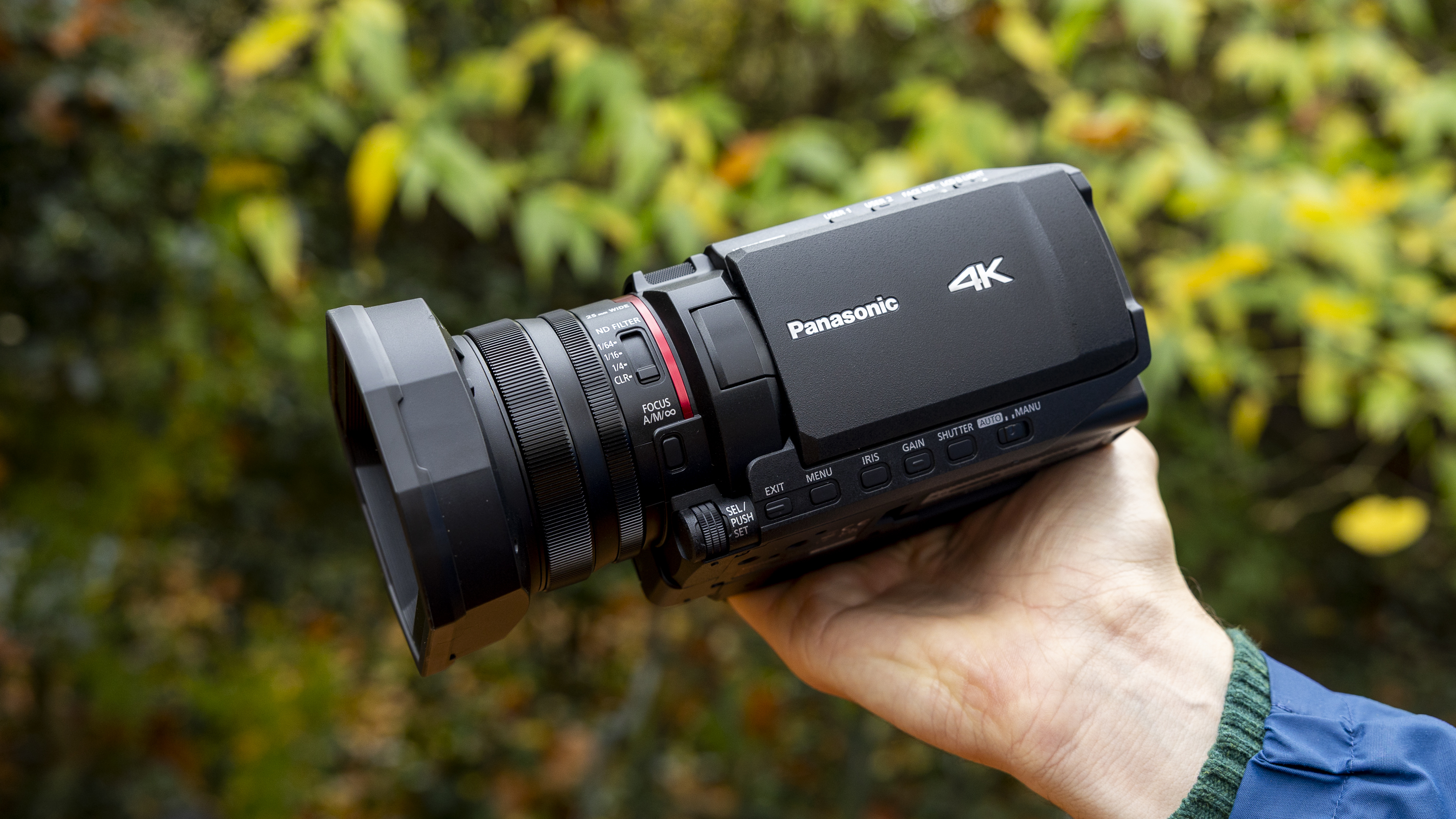 The Panasonic HC-X1200 camcorder held by a female photographer against an orange autumnal backdrop