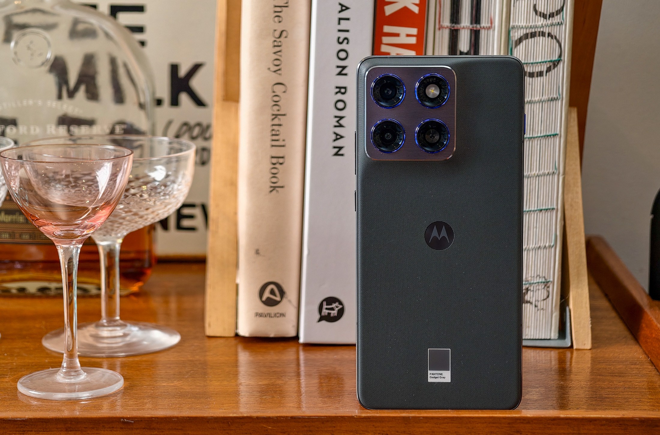 Photo of Motorola Edge 70 standing on a wooden table in front of some cookbooks