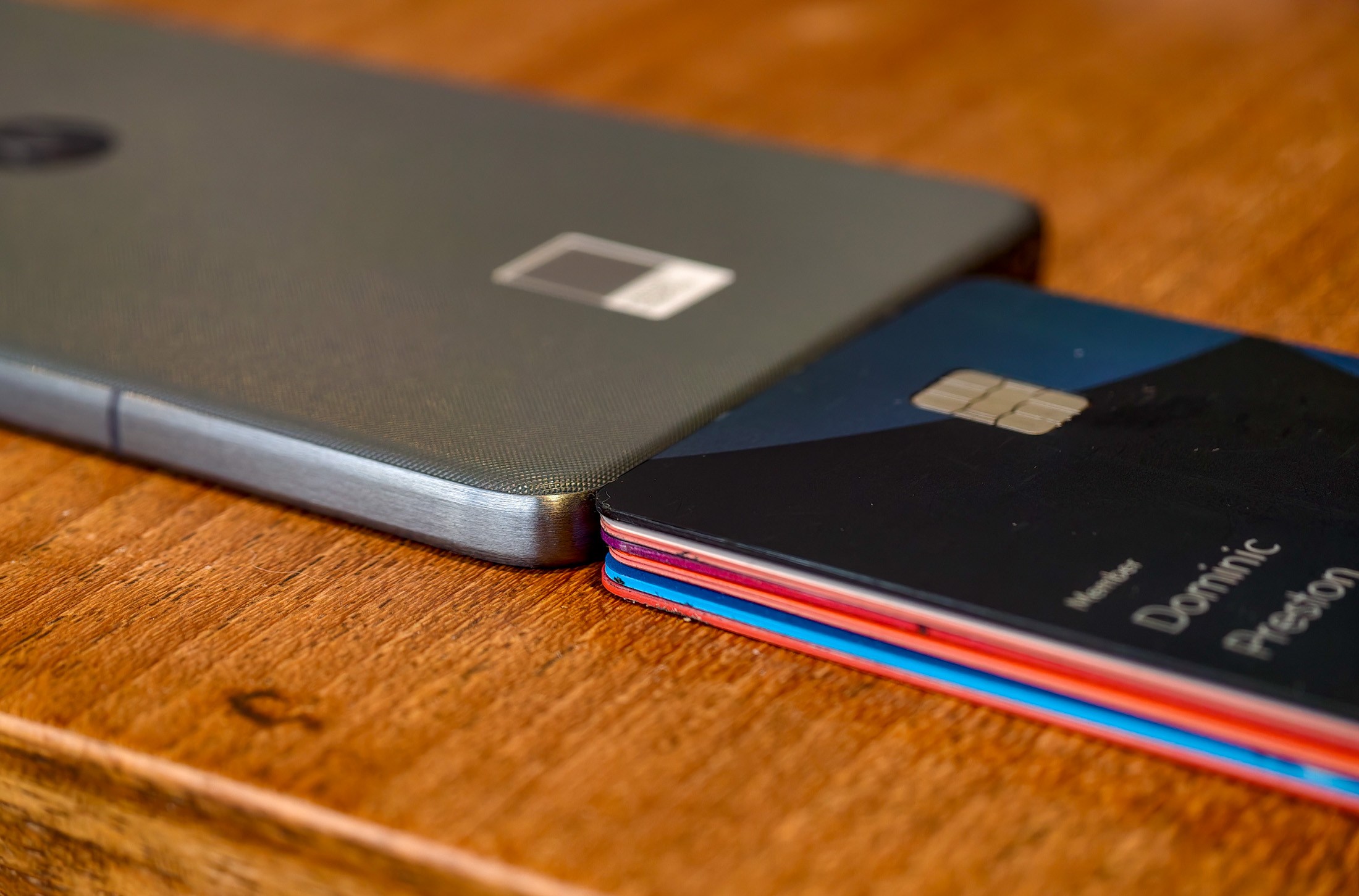 Photo of Motorola Edge 70 lying on a wooden table with a stack of six credit cards that is the same thickness