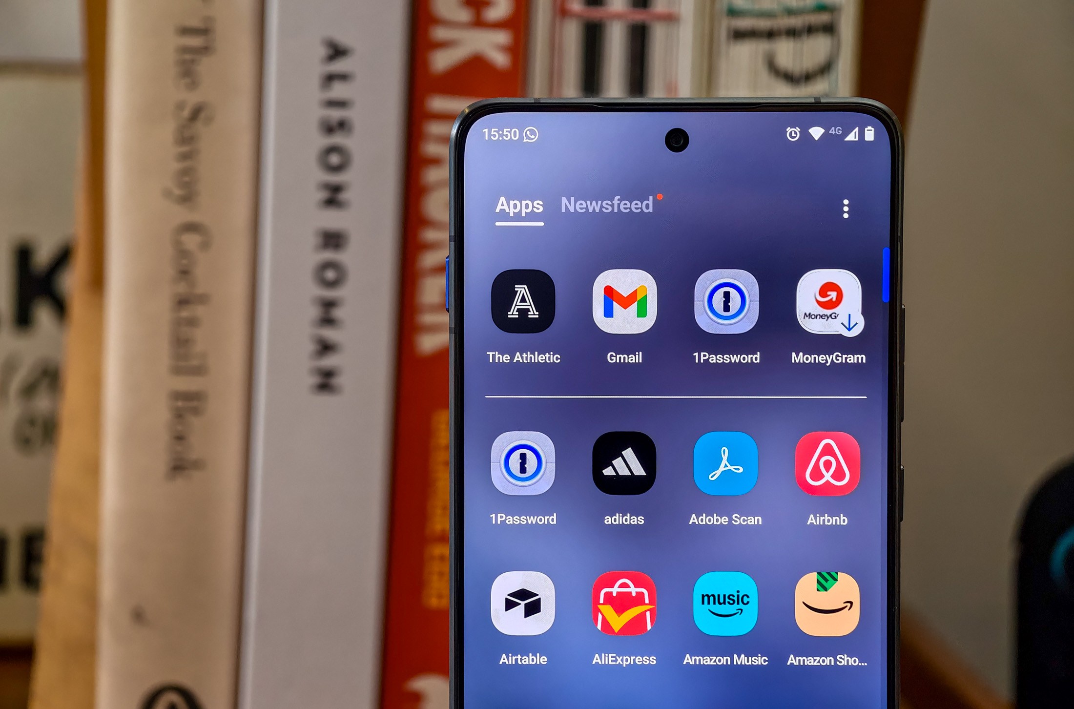 Photo of Motorola Edge 70 standing on a wooden table in front of some cookbooks, showing the app drawer with an ad to download MoneyGram