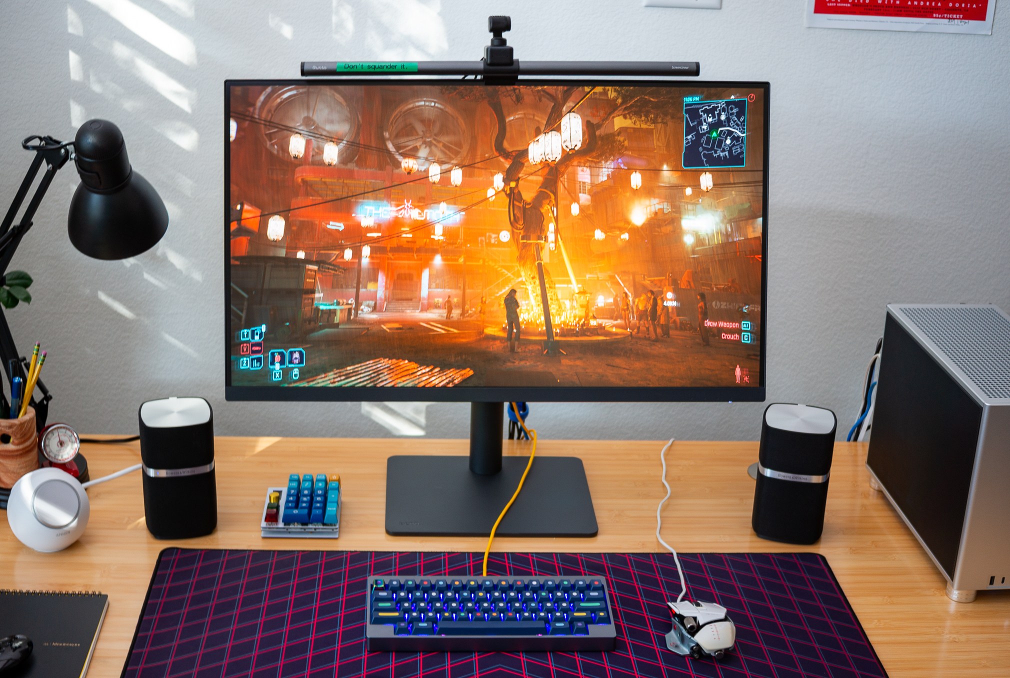 a 32-inch monitor on a wooden desk, displaying a night scene from cyberpunk 2077.