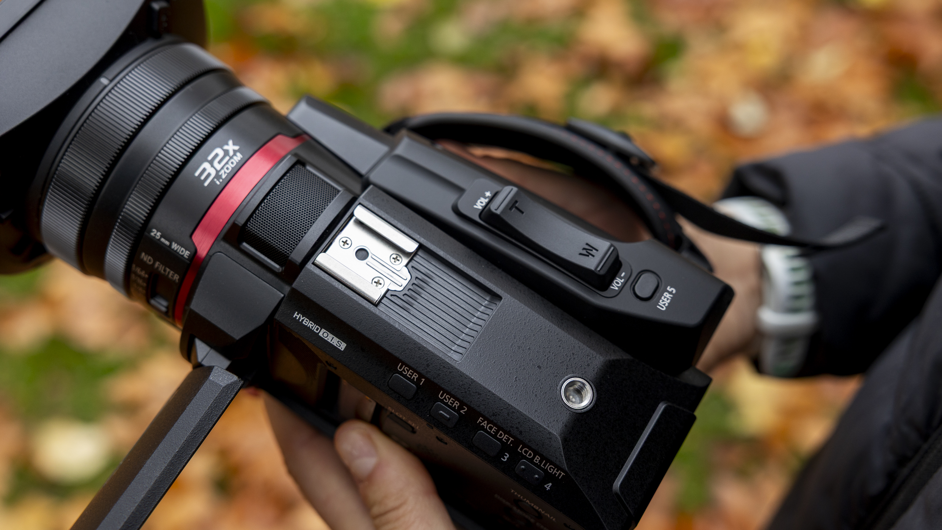 The Panasonic HC-X1200 camcorder held by a female photographer against an orange autumnal backdrop