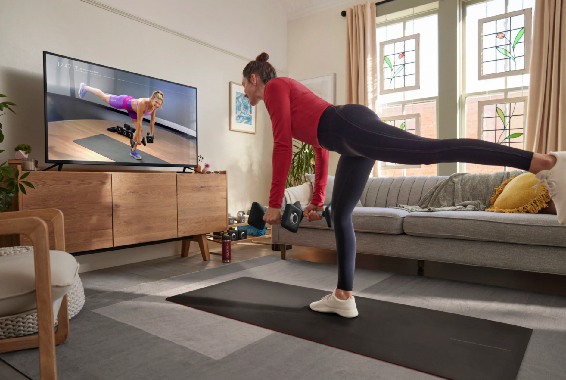 Person stretching in front of TV streaming Peloton subscription content.