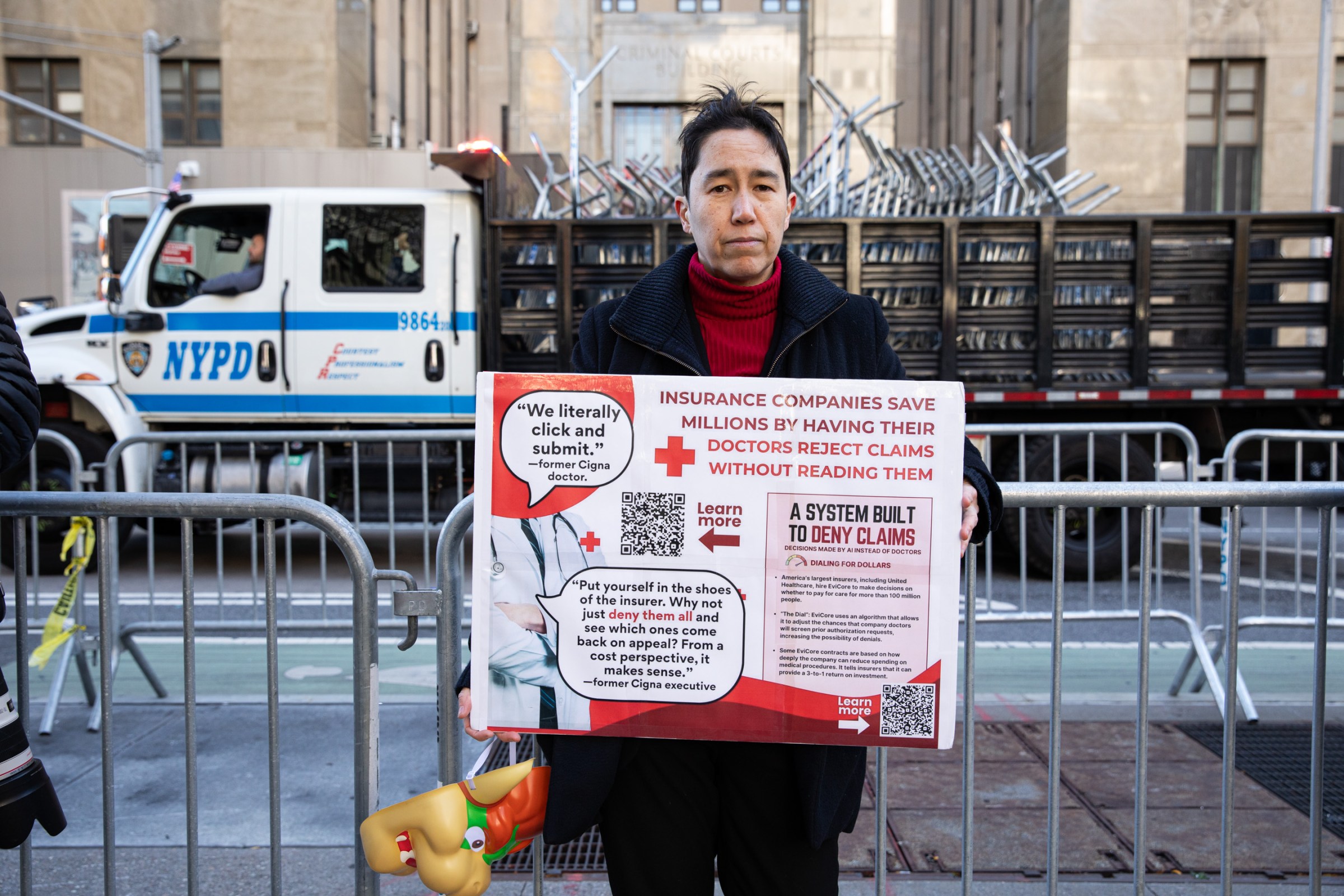 Ico Ahyicodae, an organizer with healthcare reform group People Over Profit NYC, outside the courthouse. They are holding a sign about healthcare claims rejections.