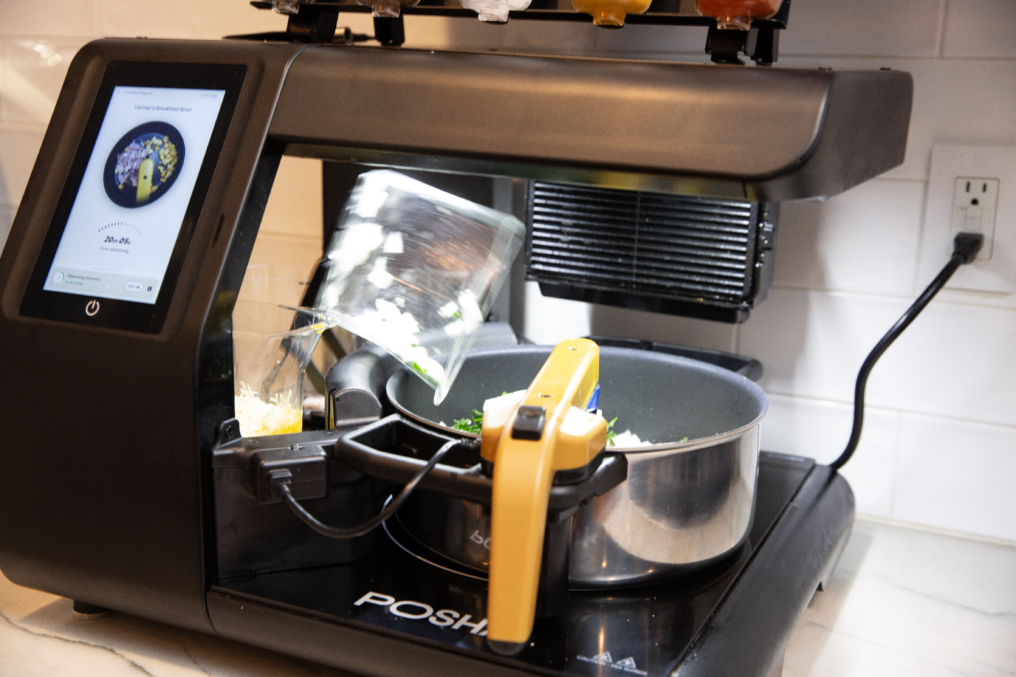 3/4 view of a Posha cooking robot sitting on a marble countertop.