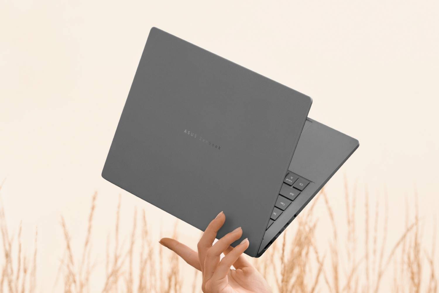 A hand holding the Zenbook A14 between their fingers.