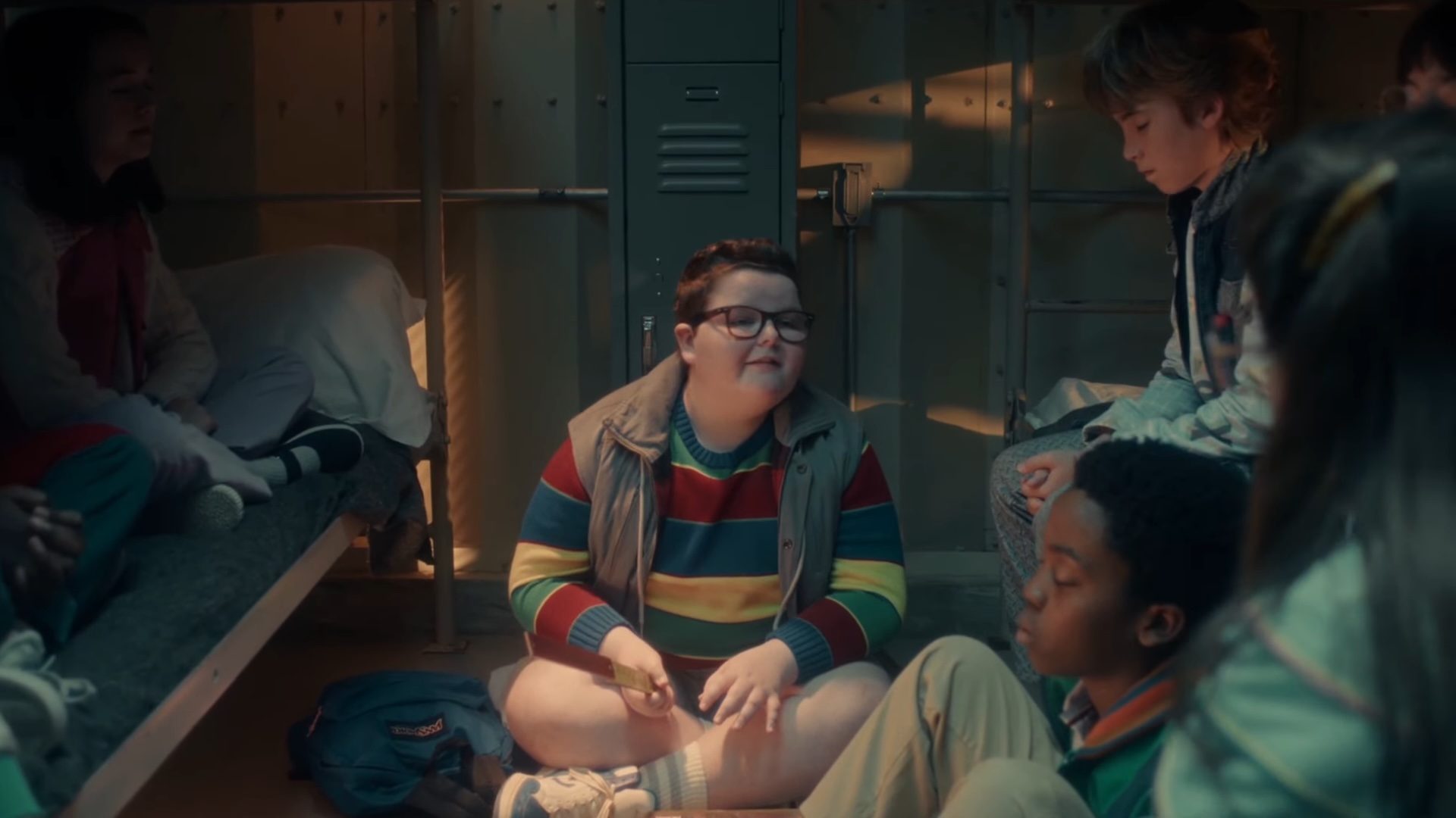 Jake Connelly as Derek sitting with a group of children in Stranger Things season 5.