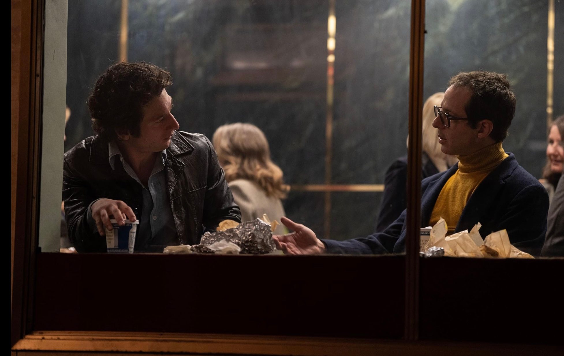 Two men sit across from each other at a restaurant.