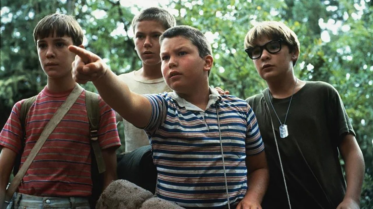 The four main boys in Stand By Me, with one of them pointing and them all looking.