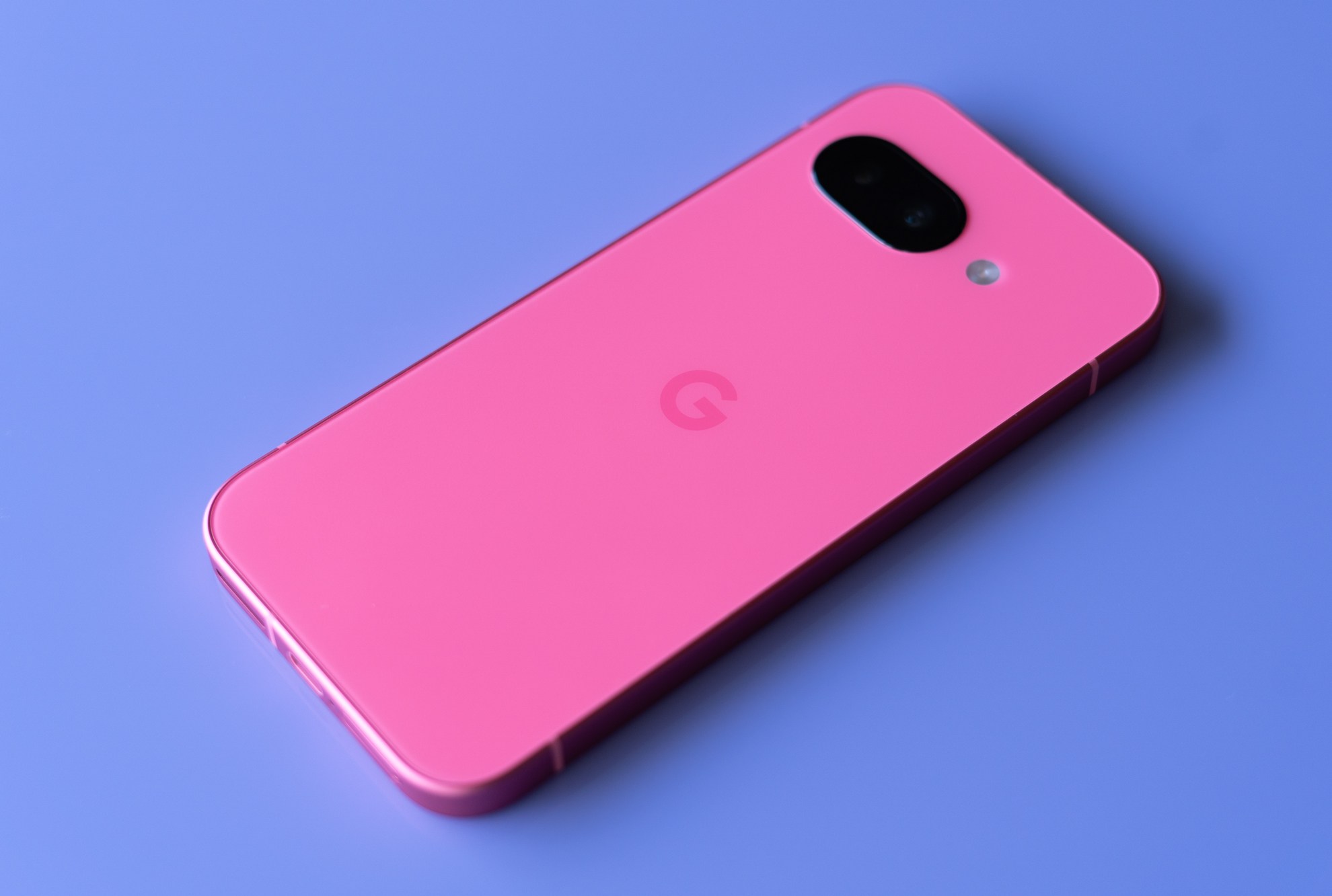 Google Pixel 9A in peony pink on a purple background.