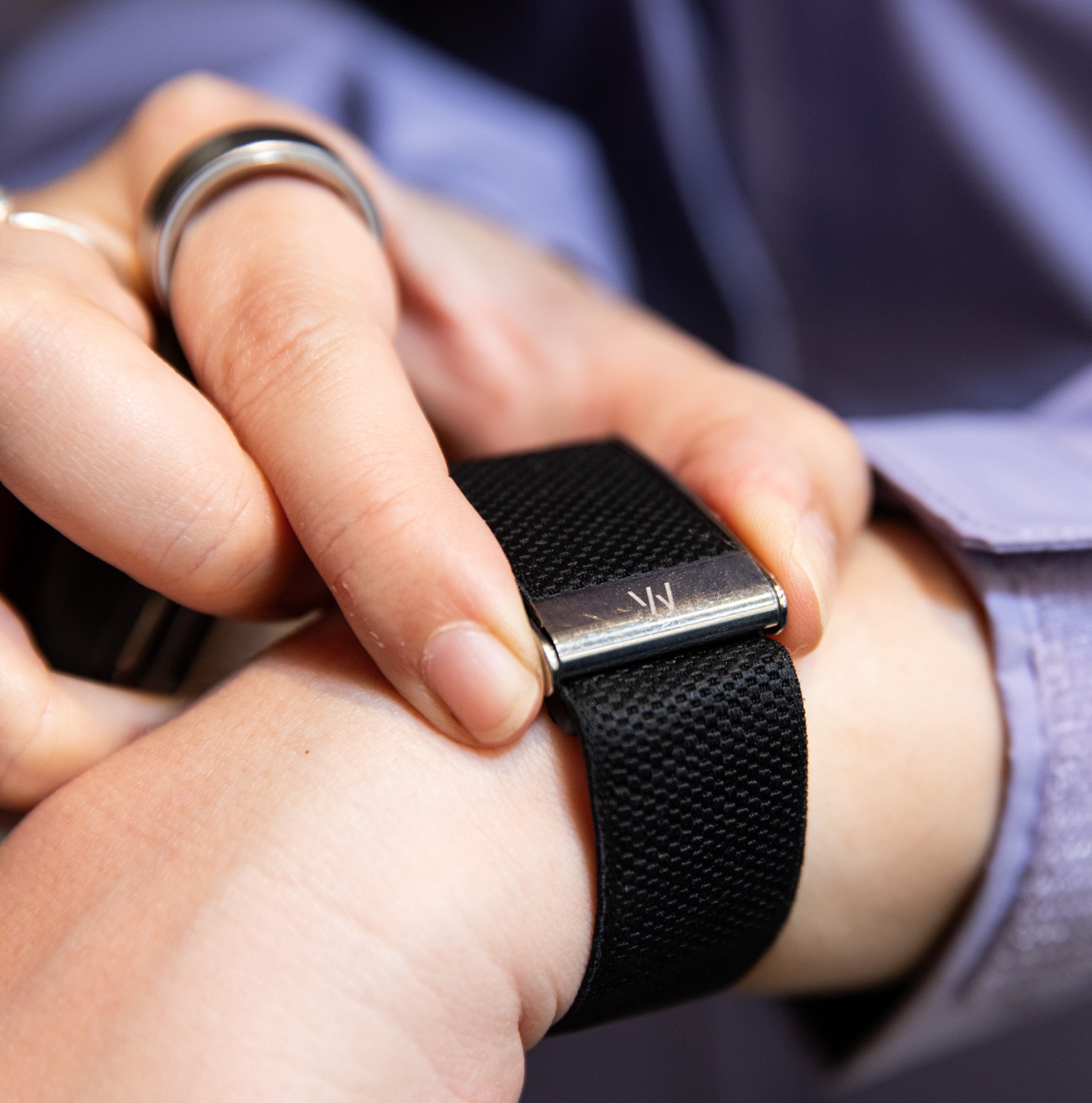 Senior reviewer Victoria Song wearing the Whoop MG while wearing a light purple jacket. Her fingers are placed on the edges of the Whoop device for an EKG test