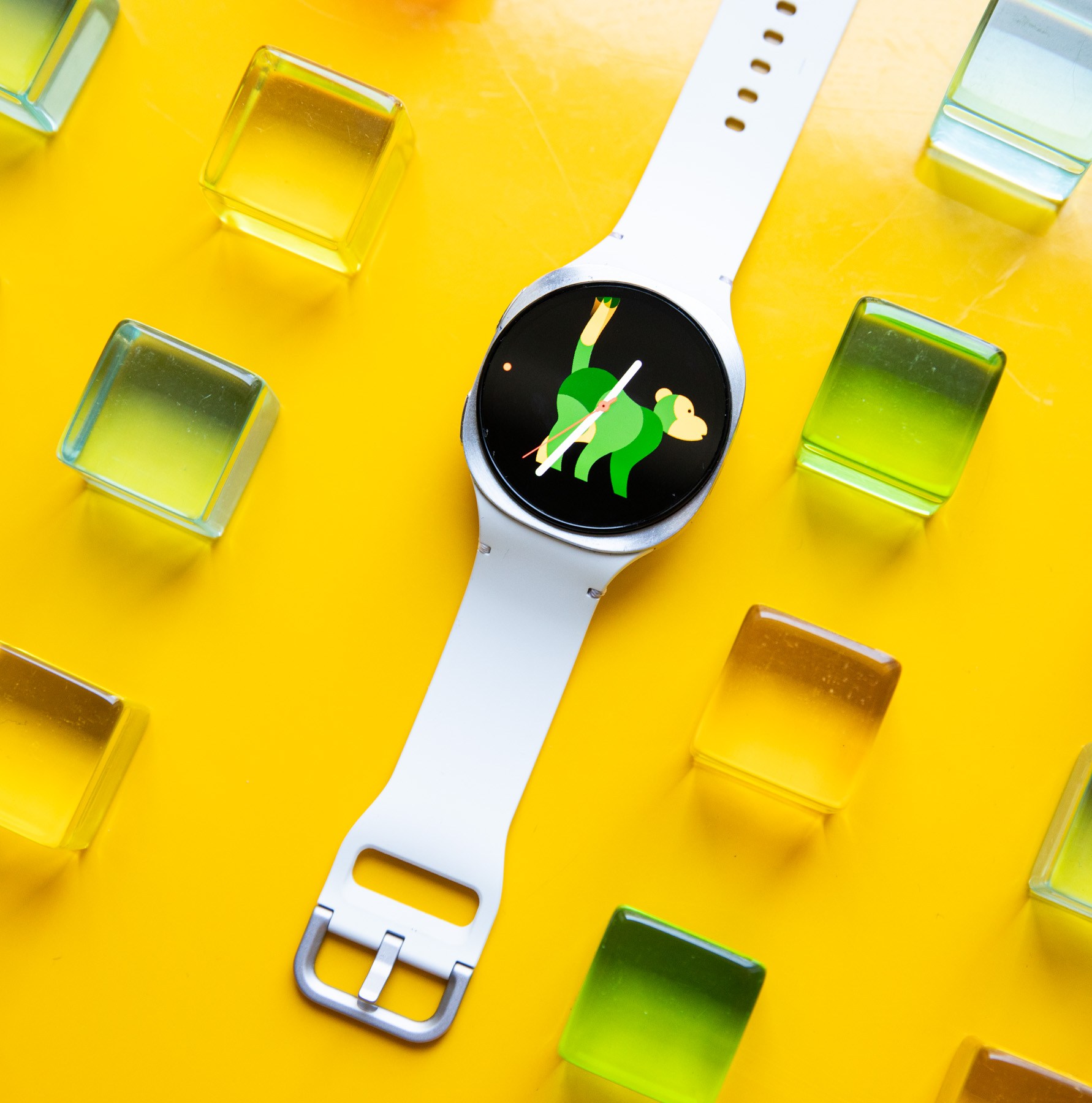Wide view of the Samsung Galaxy Watch 8 on a yellow table with colorful green, yellow, orange, and pink acrylic blocks around it.