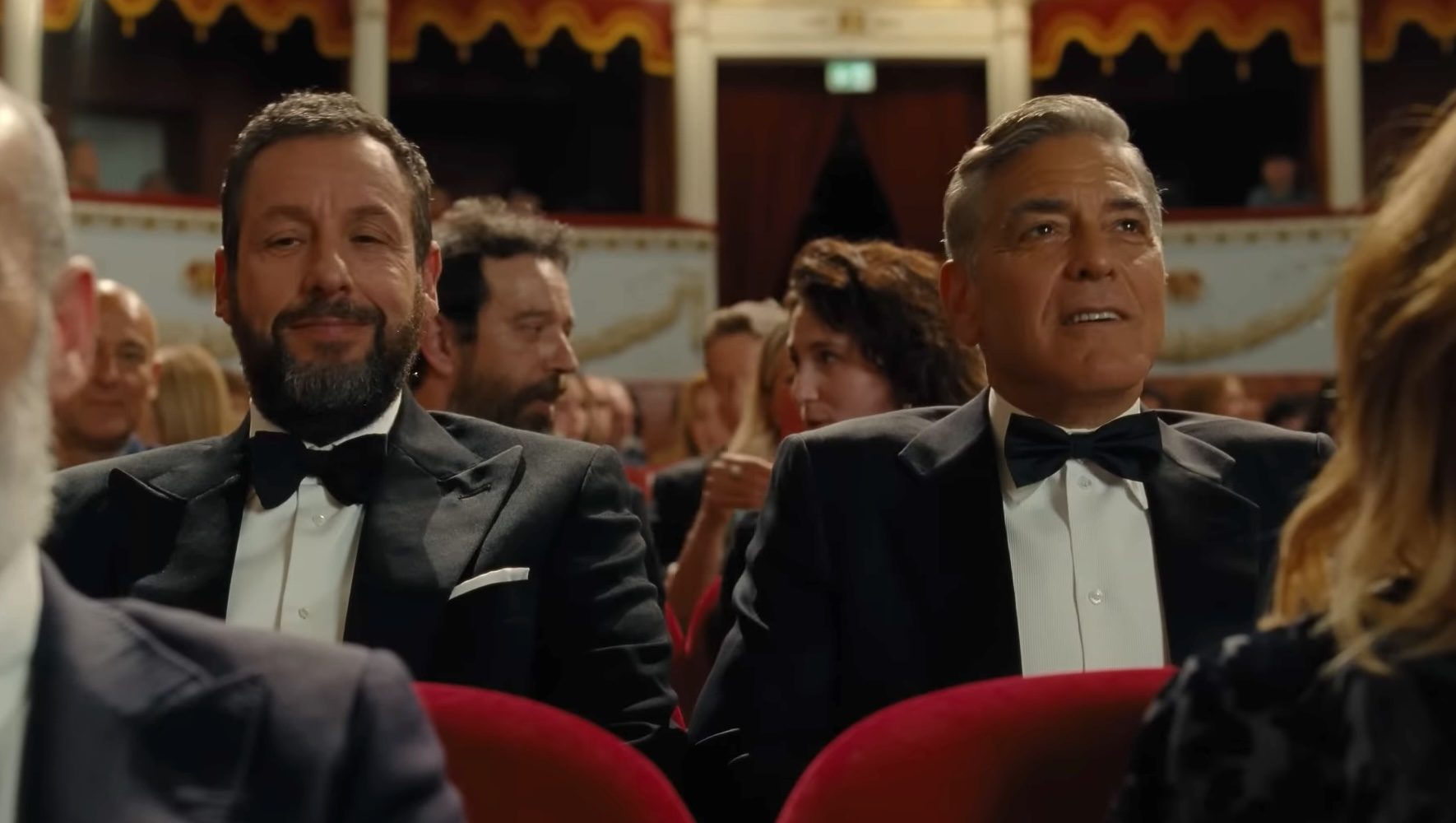 Adam Sandler and George Clooney sitting in a movie theater together in Jay Kelly.