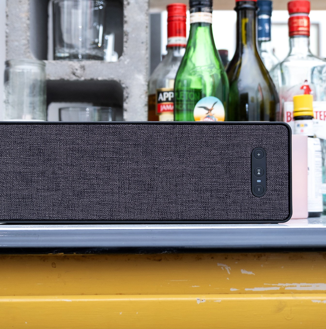 A photo of the Ikea Symfonisk Bookshelf Speaker with bottles behind it.