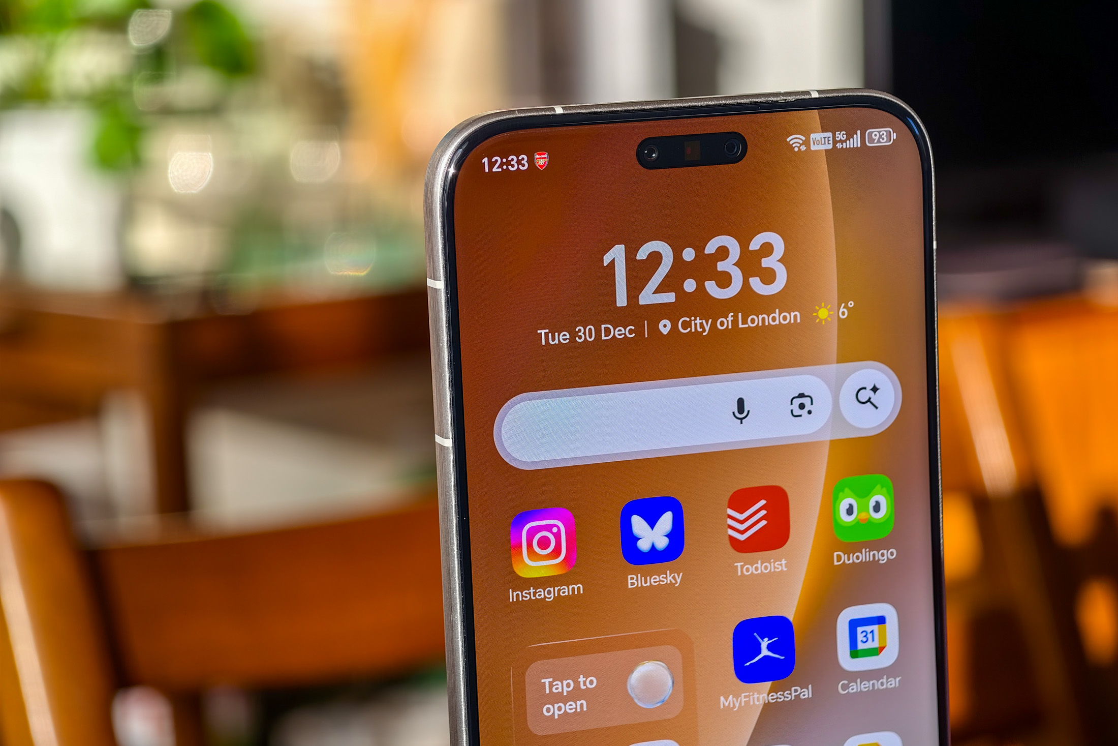 Photo of Honor Magic 8 Pro on a wooden table showing the top half of the home screen