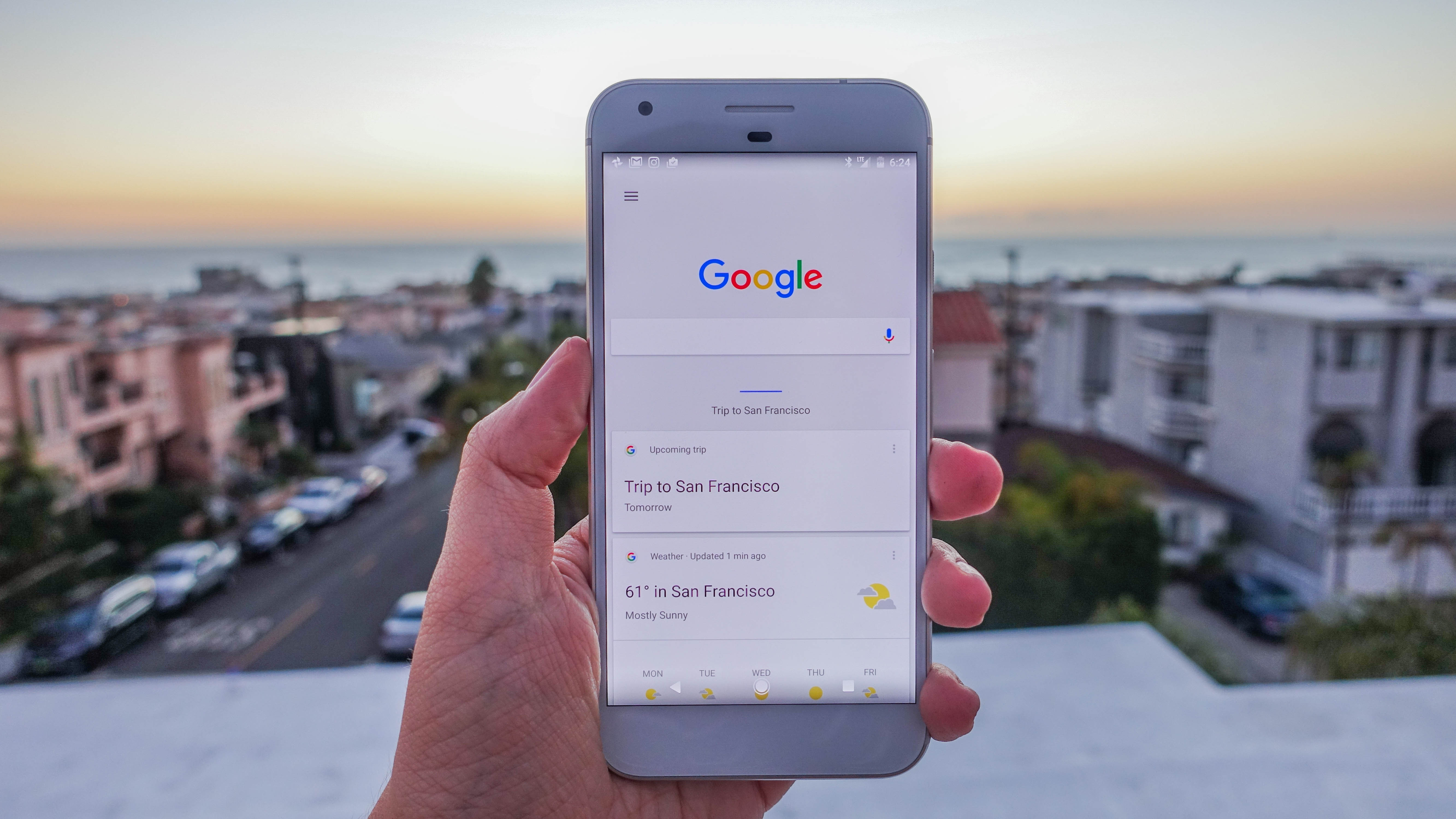 Google Pixel XL open to the Google app, cityscape in the background