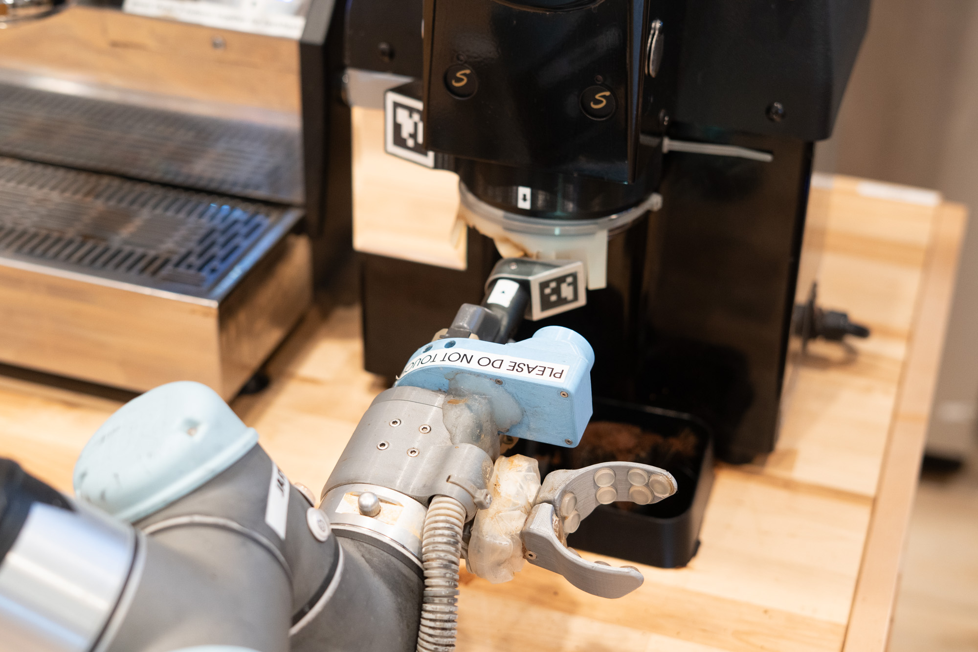 Robot barista inserting portafilter in espresso grinder