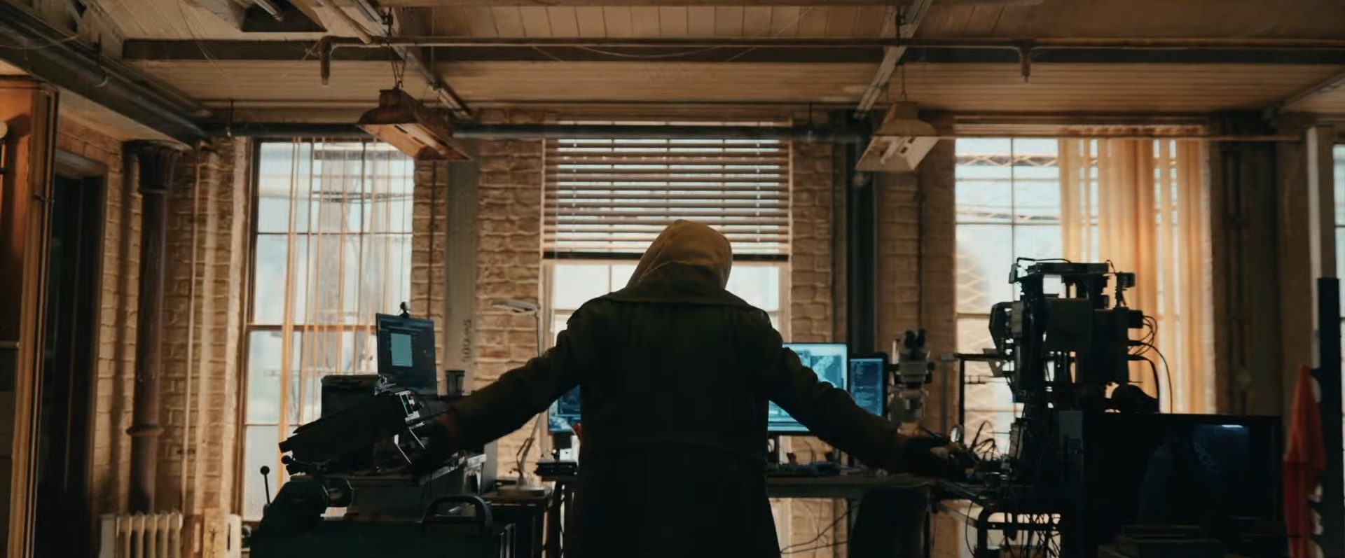 A hooded figure with their arms spread out in front of a computer in the Marvel film, Spider-Man Brand New Day.