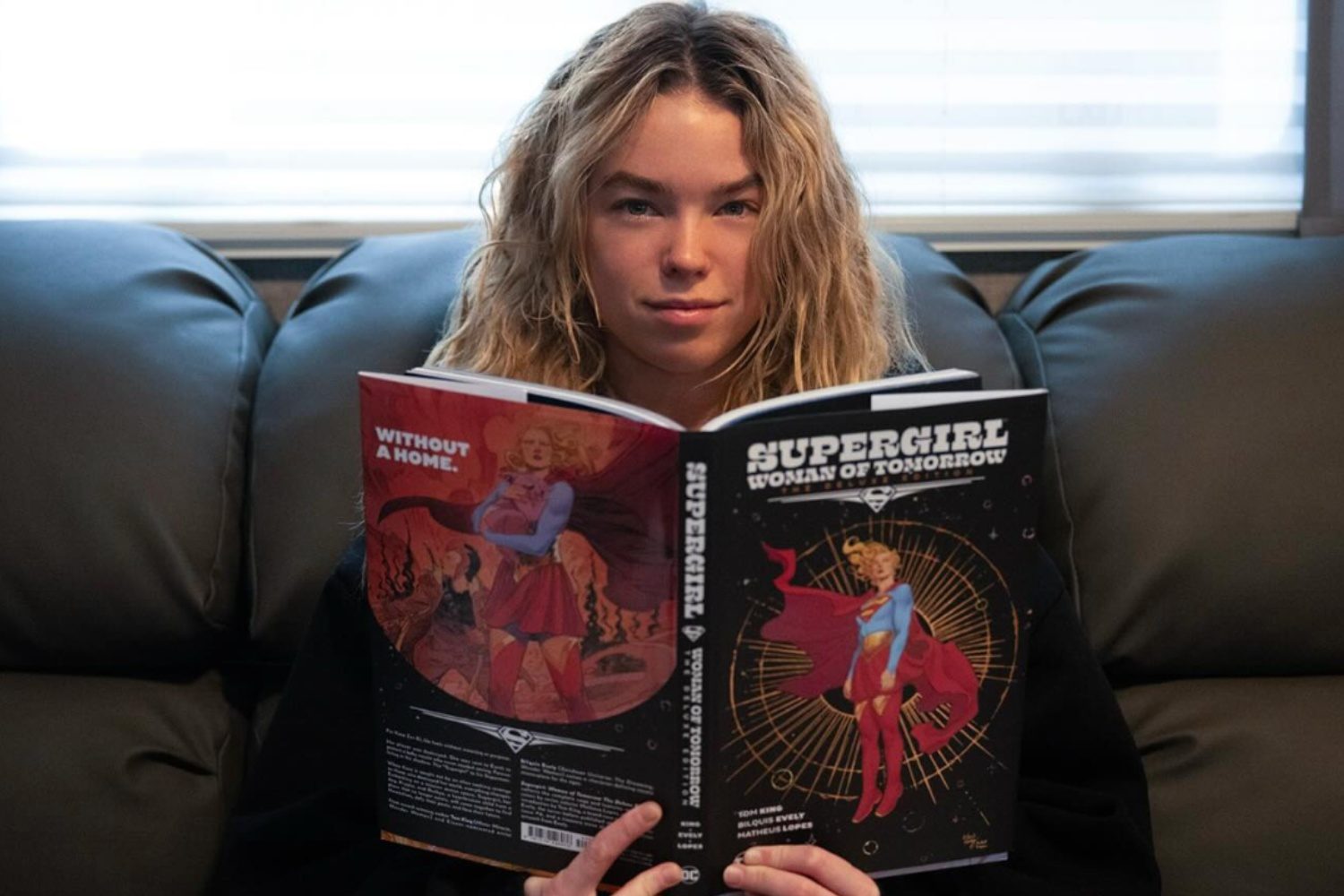 Milly Alcock holds a book as Supergirl.