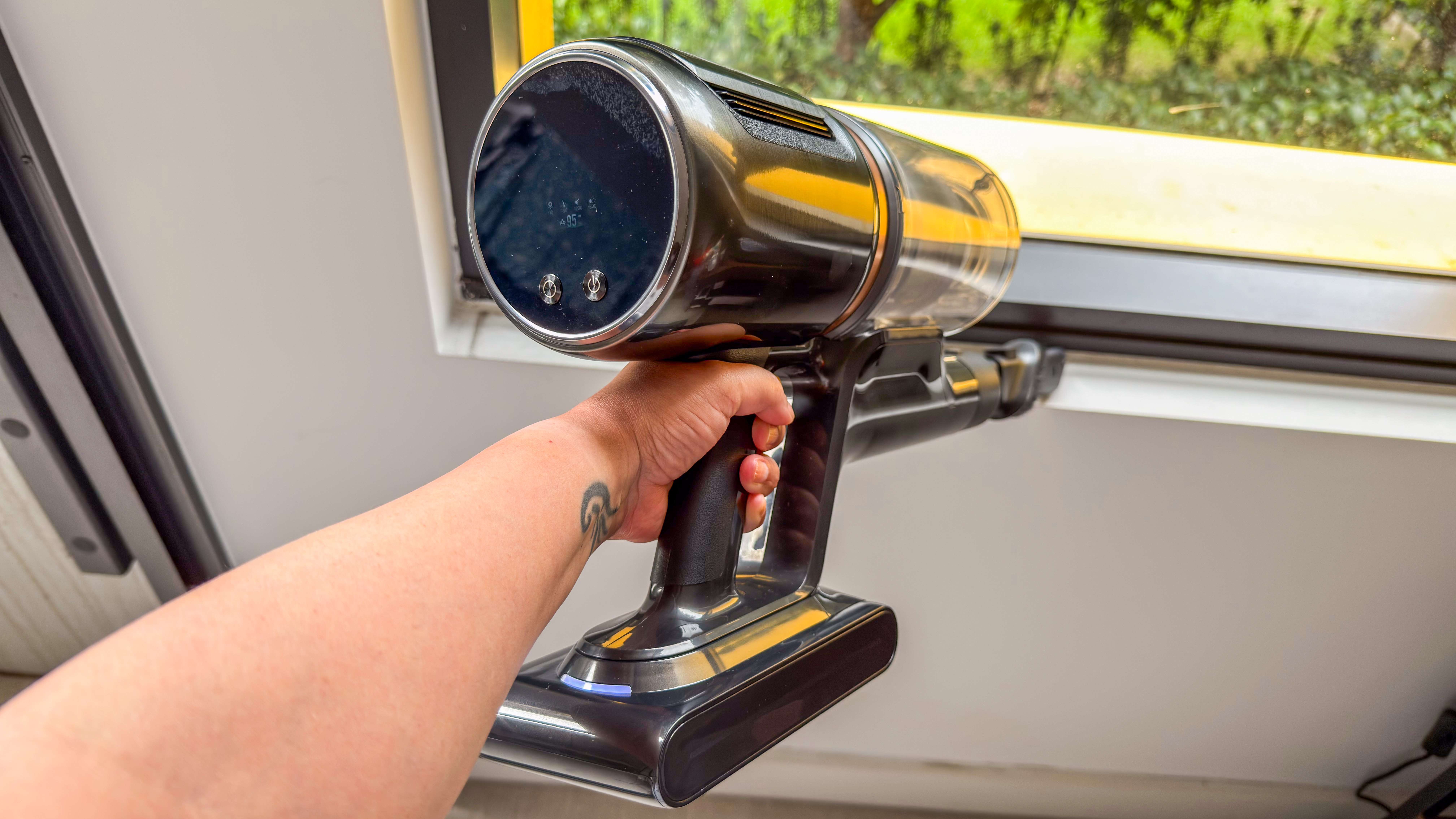 A person using the Dreame Z50 Station handheld unit with the crevice tool on a window sill