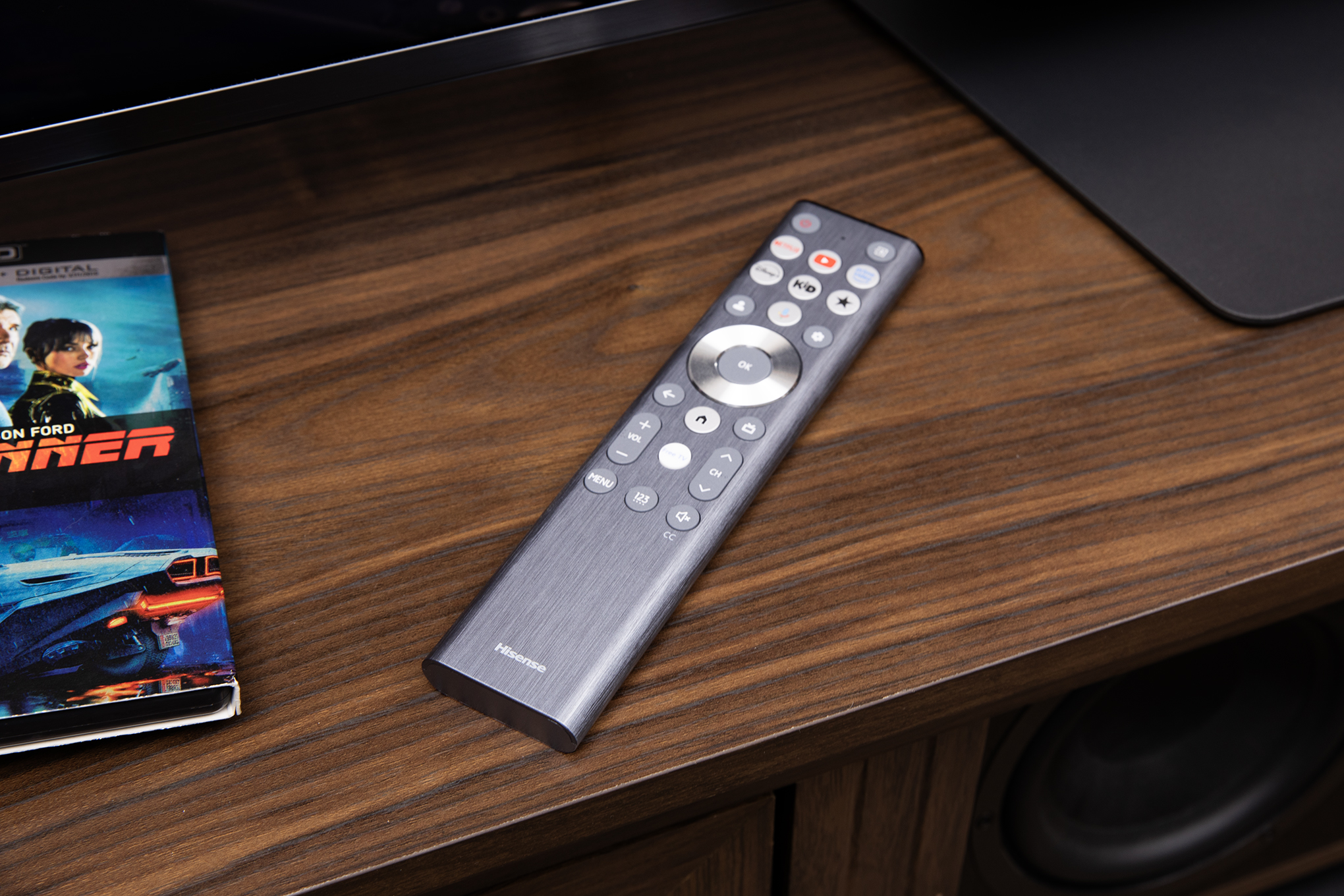 Hisense UR9 RGB LED TV remote sitting on a wooden cabinet.
