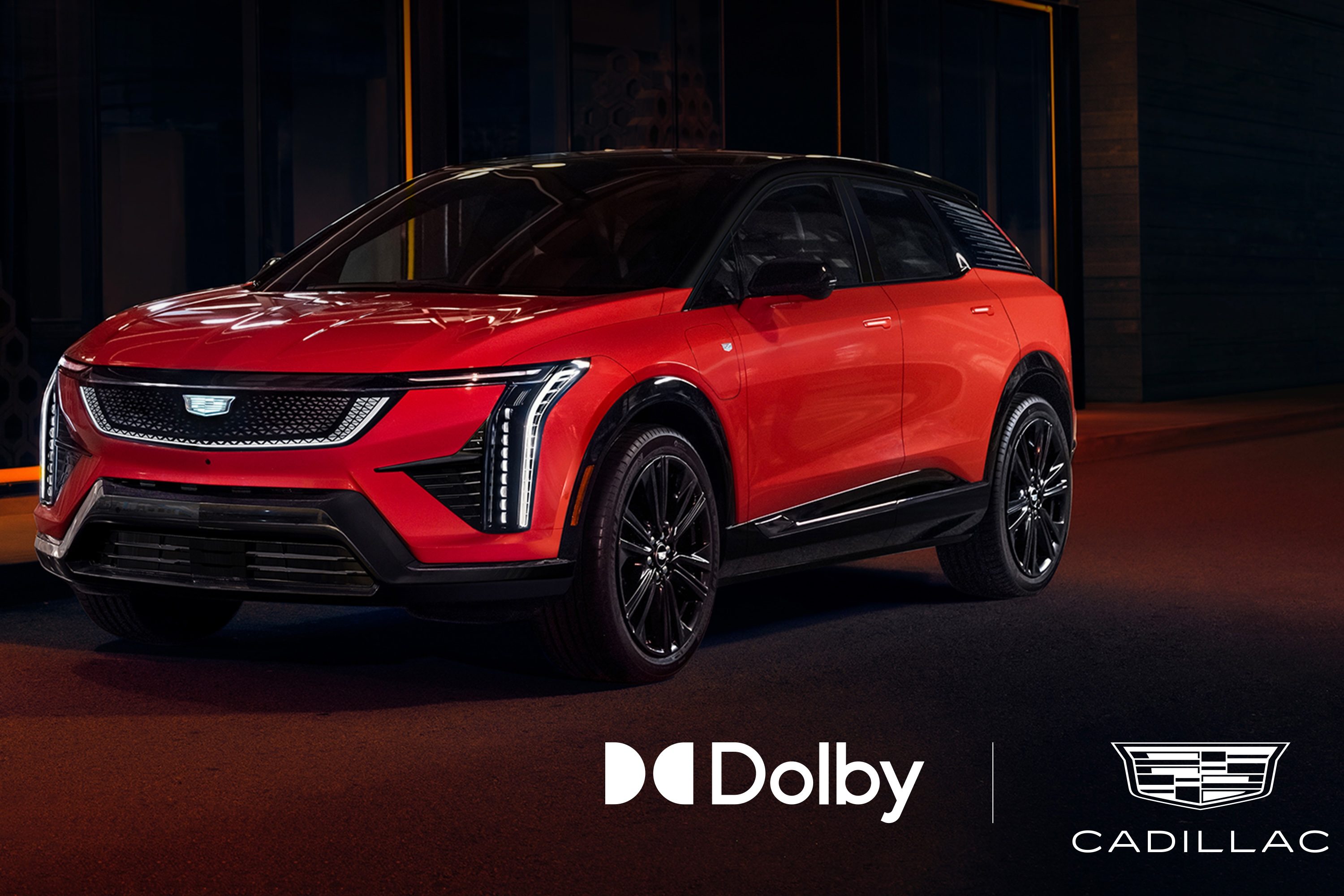 A red Cadillac EV on a dark background with the Dolby and Cadillac emblems underneath.