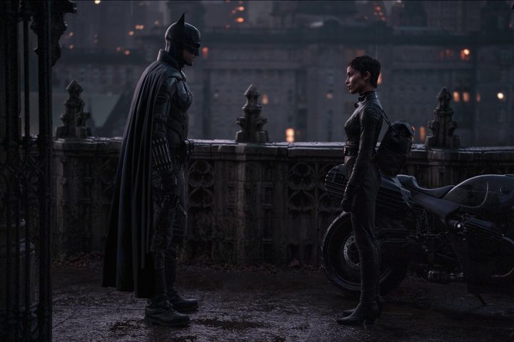 Batman stands across from Catwoman and looks at her.