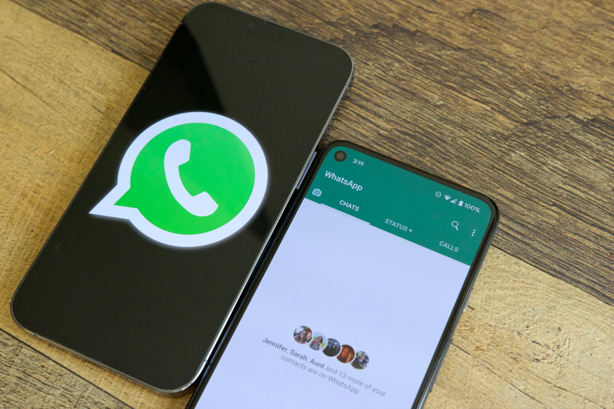Two phones on a table next to each other. One is showing the WhatsApp logo, and the other is running the WhatsApp application.