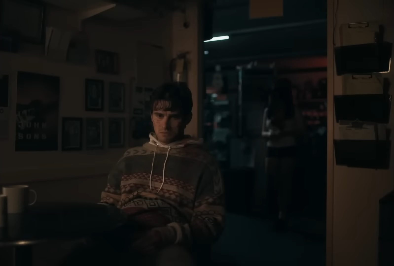 Bear (Michael Johnston) sitting with Nikki (Inde Navarrette) standing behind him in the horror film, Obsession.