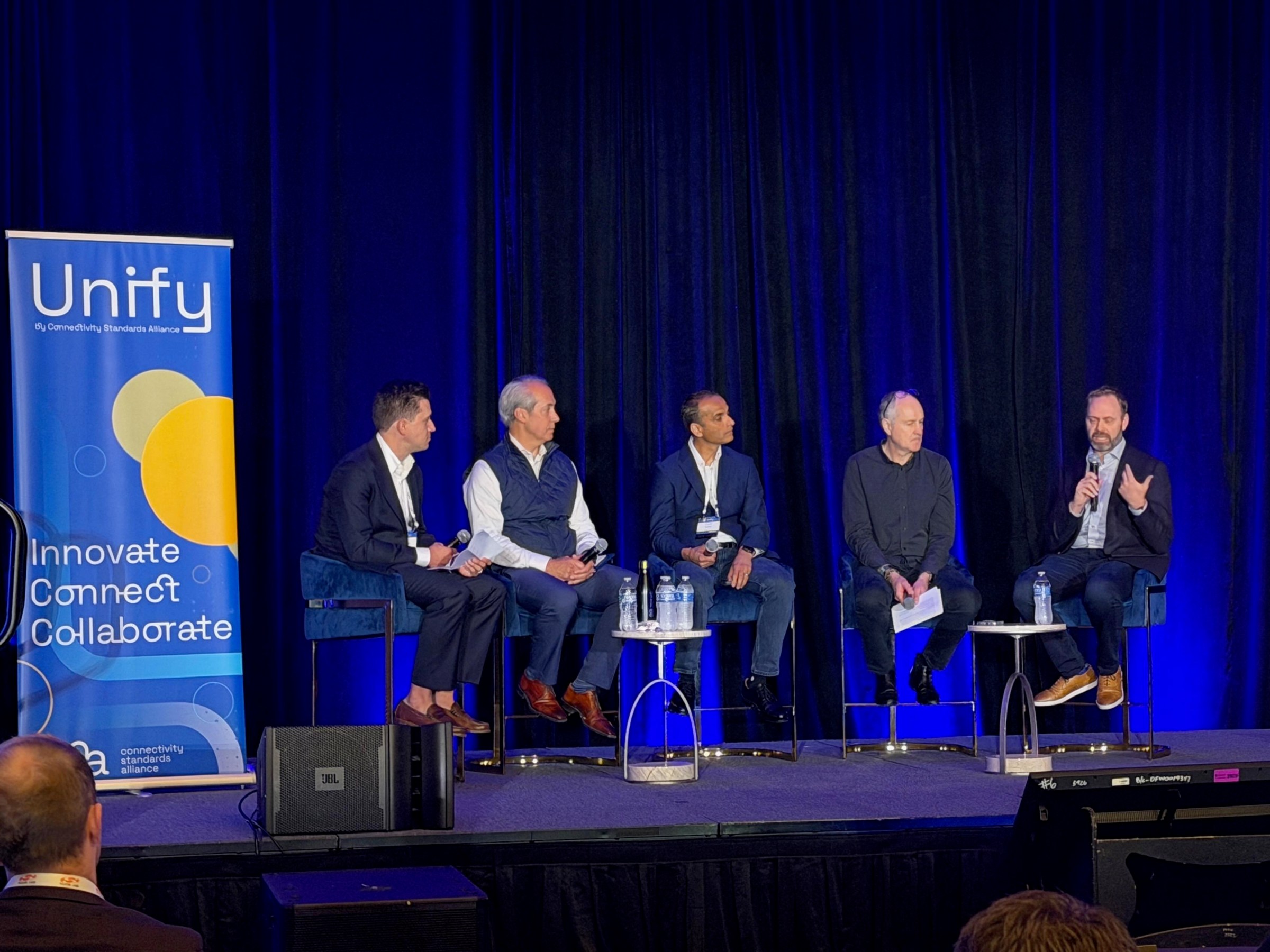 Dan Wroclawski of Consumer Reports moderates a panel with Tobin Richardson of the CSA; Vividh Siddha, president of Thread Group and Director of software engineering at Apple; Neville Meijers, CEO of Bluetooth SIG; and Kevin Robinson, CEO of Wi-Fi Alliance.