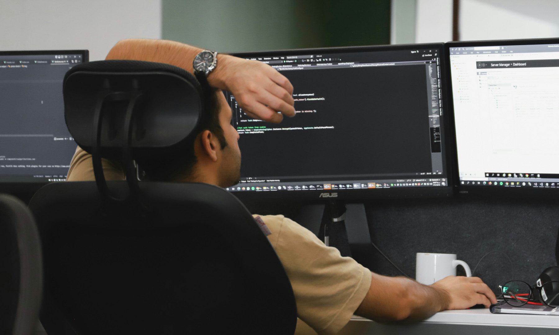 Man working in front of computer with 3 screens
