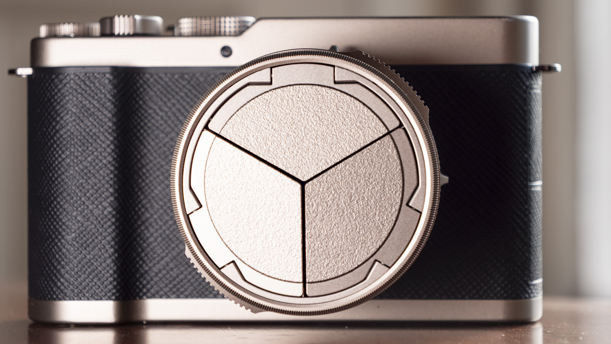 Titanium Gold special edition of the Panasonic Lumix L10 compact camera, on an antique wooden table 