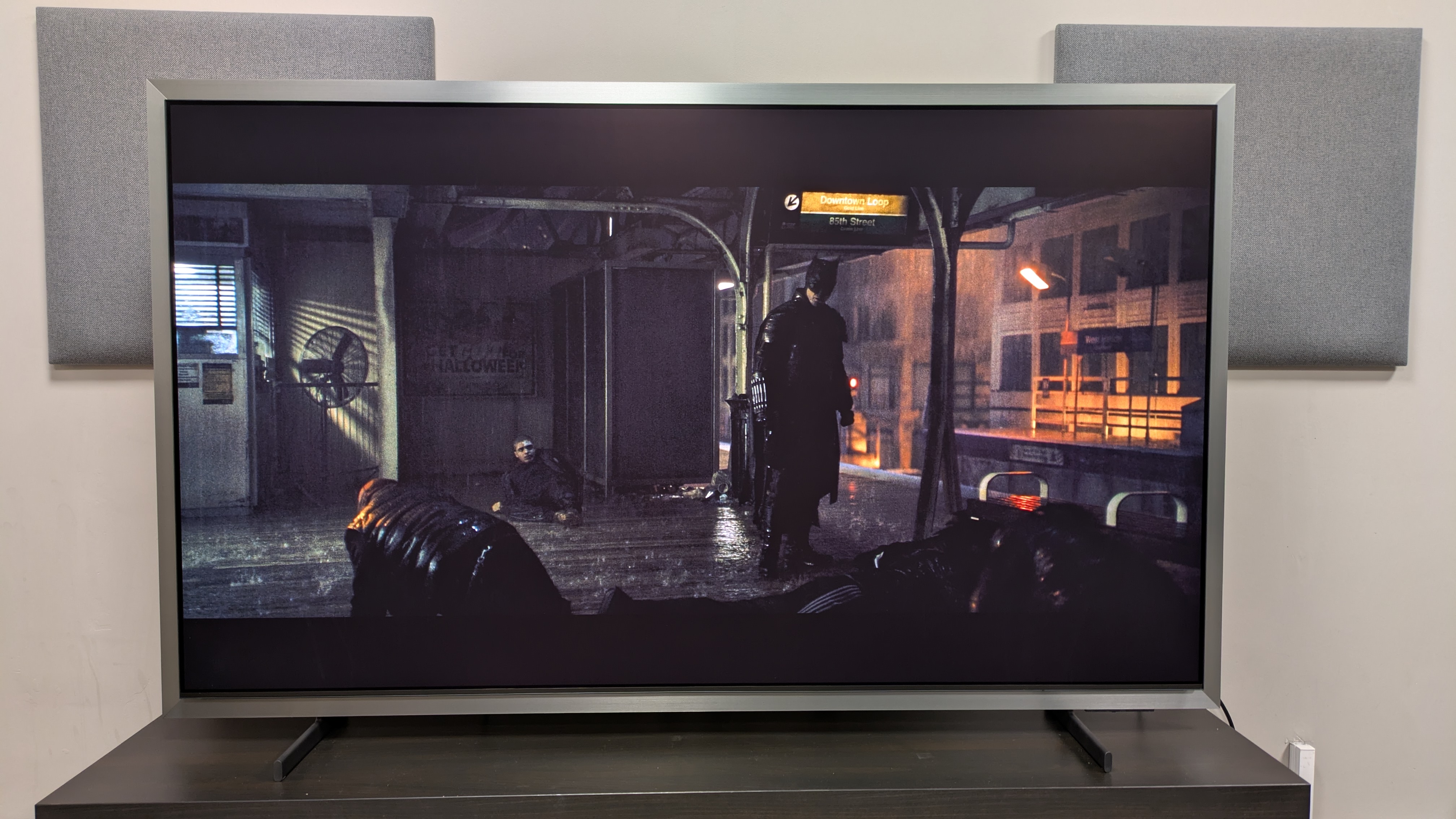Samsung S99H with a shot of Batman stood on a subway platform from The Batman. The TV is set to Movie mode, and the picture is clear in very bright conditions