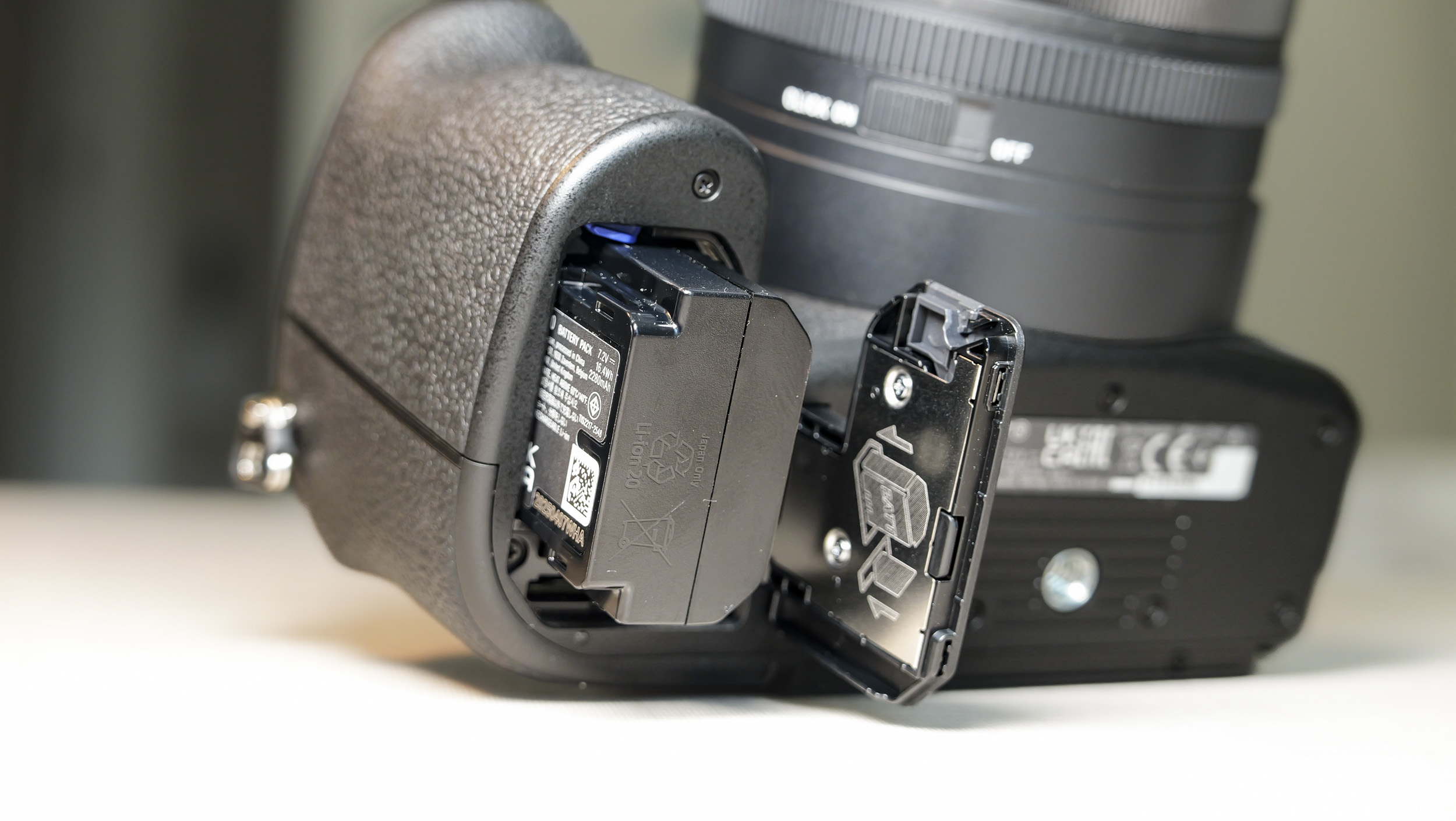 Closeup of the Sony RX10 V bridge camera's  battery door, and the battery is half out