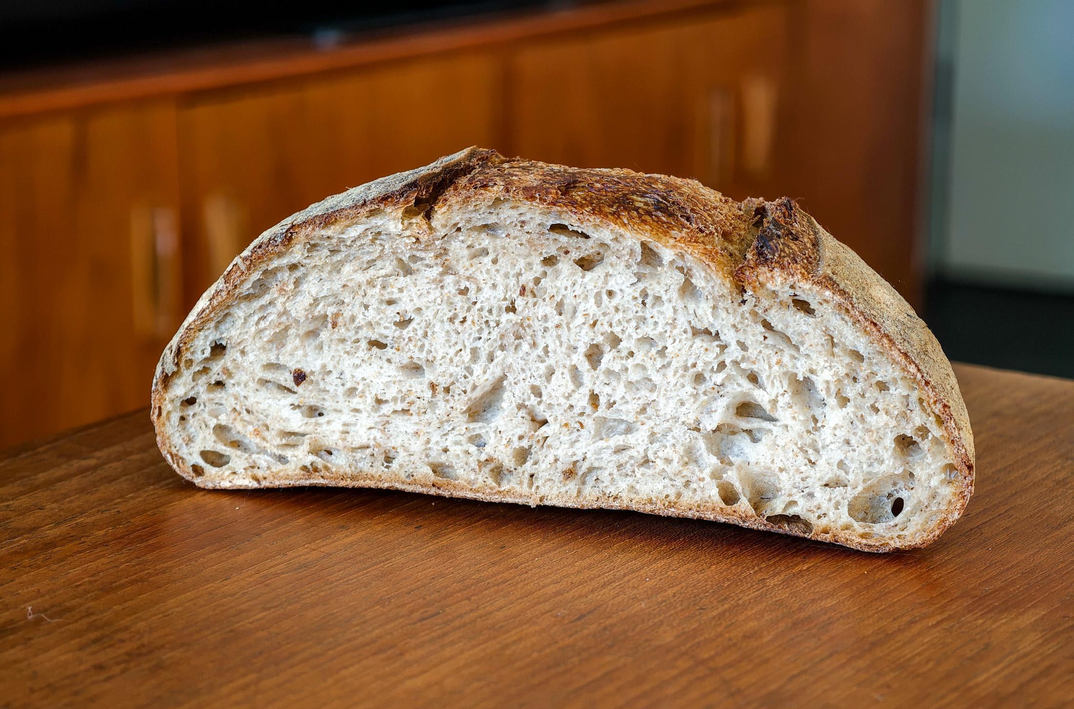 Photo of a loaf of sourdough bread cut in half on a wooden table