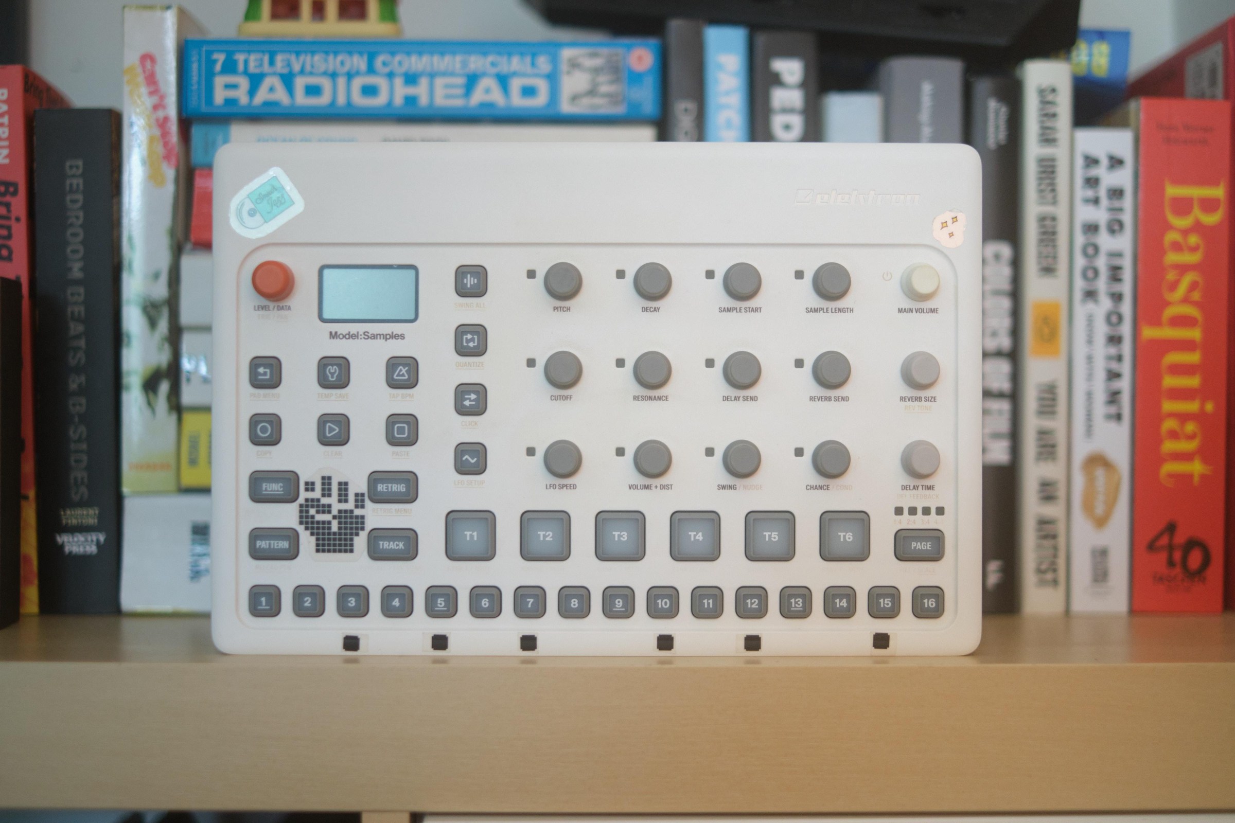 The Elektron Model:Samples on a shelf in front of a bunch of books and a VHS copy of Radiohead’s 7 Television Commercials.