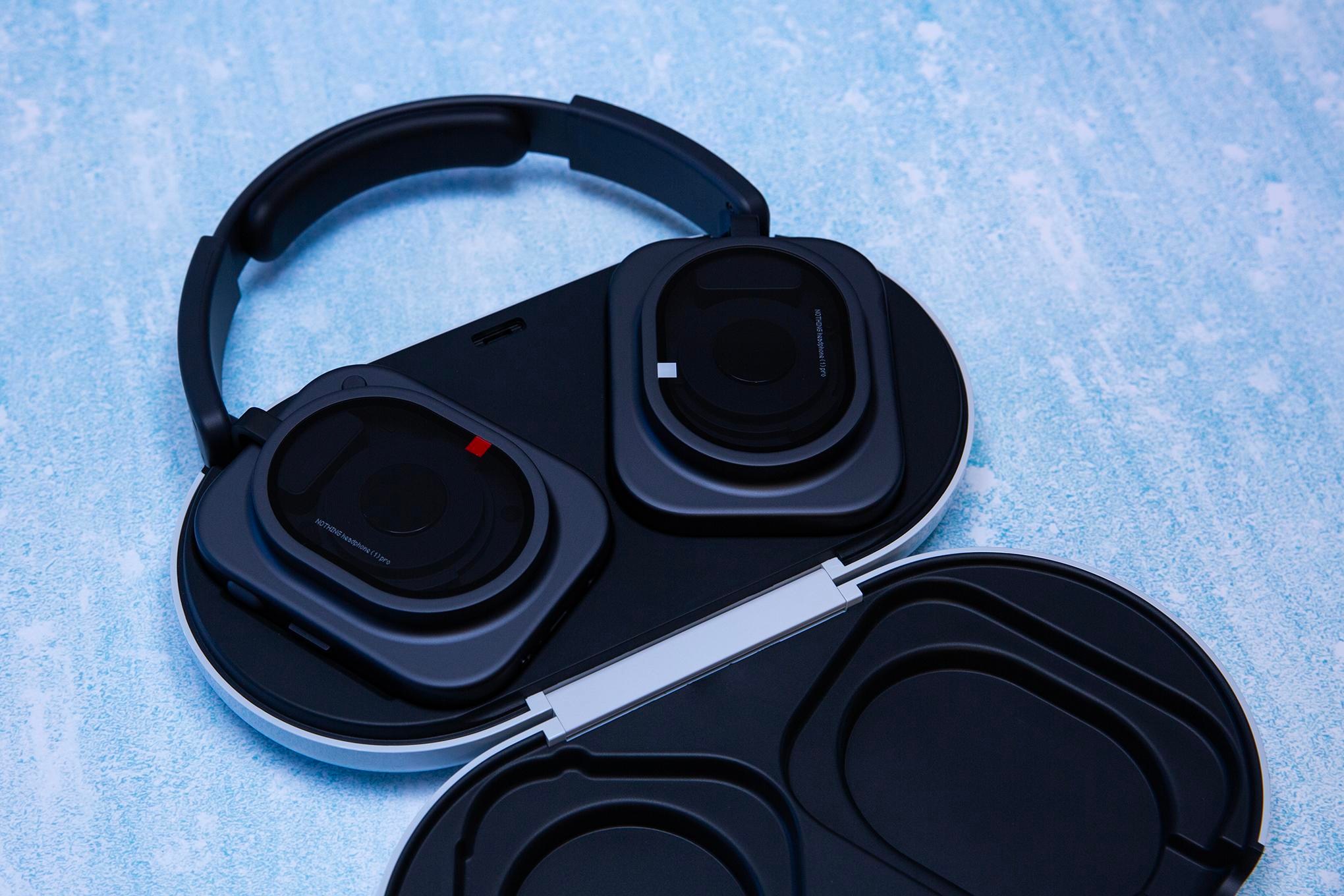 Black Nothing Pro 1 headphones sitting in an open case on a texture blue background.